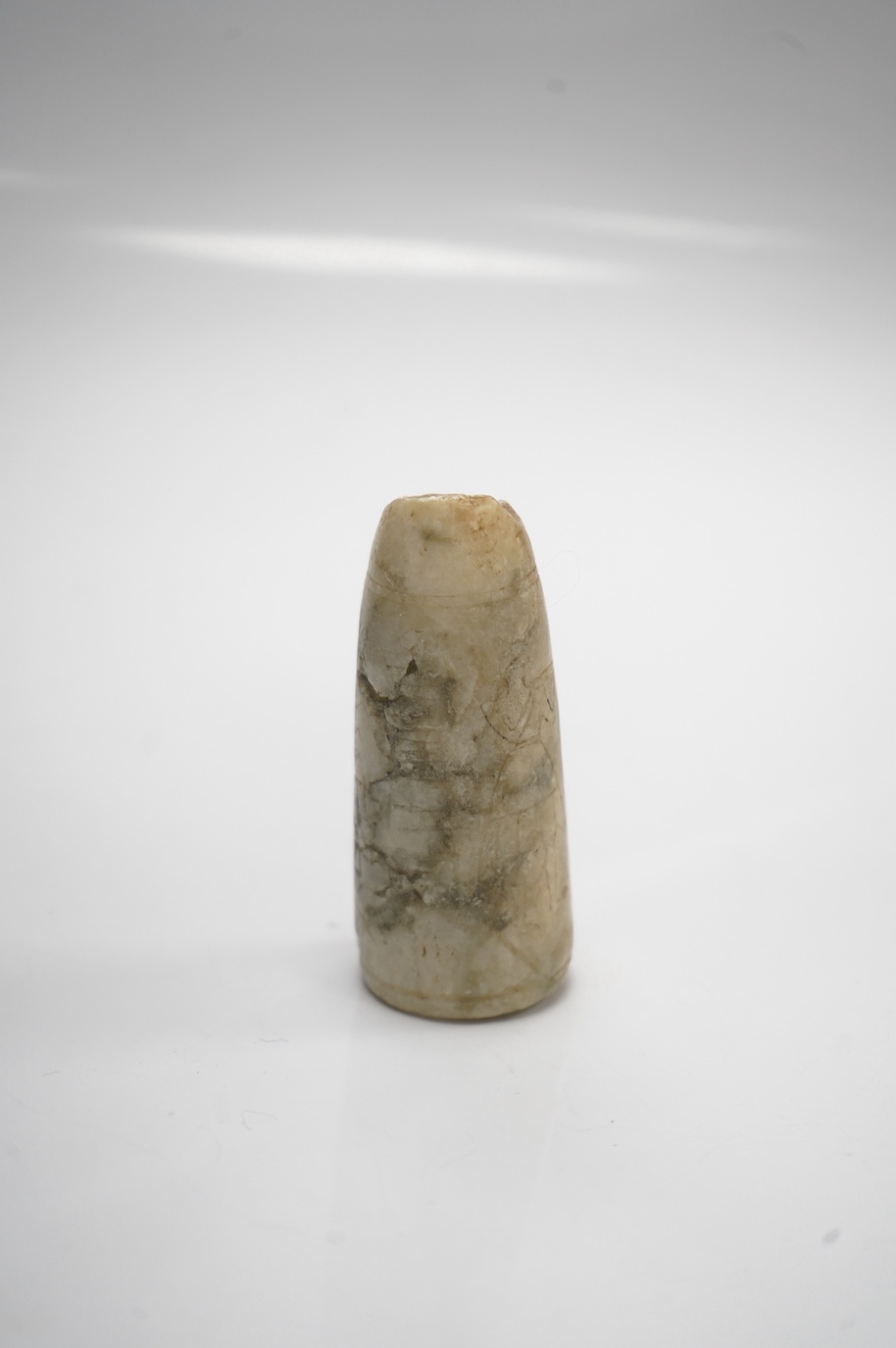 An Egyptian incised alabaster cosmetics bottle (bullet shaped), 7.5cm. Condition - restored